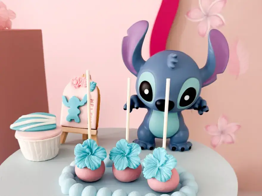 Bolo decorado com tema Stitch em tons de rosa, com cupcakes.