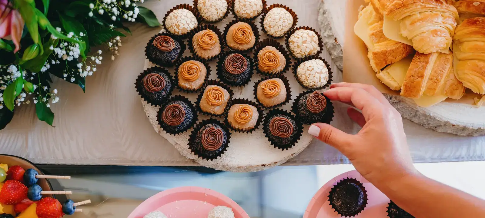 Bandeja com brigadeiros, croissants e outros doces e salgados de festa.