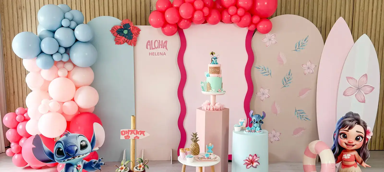 Cenário de festa premium com painéis ondulados, balões e figuras decorativas.