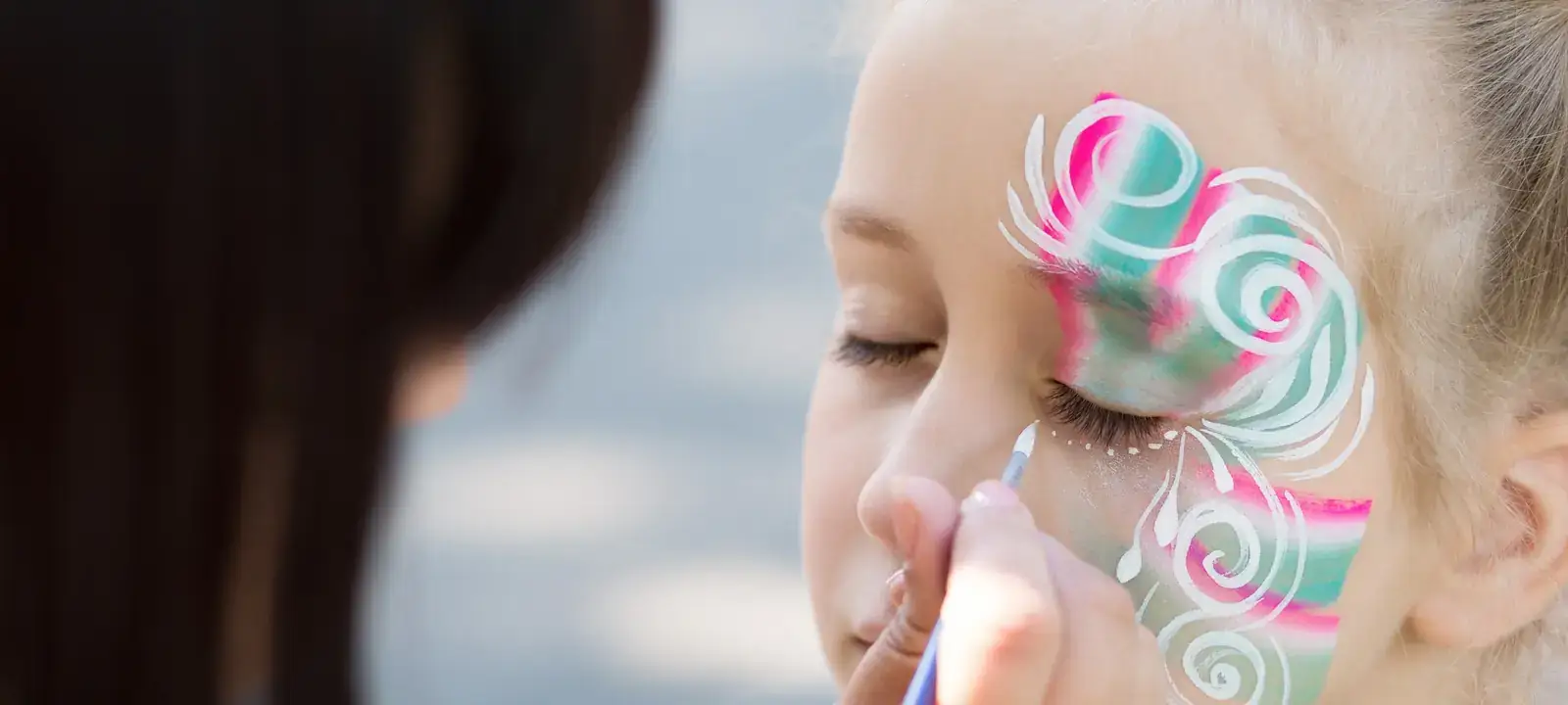 Criança a receber uma pintura facial colorida numa festa.
