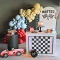 Mesa de festa com tema de carros de corrida, balões, bolo e doces.